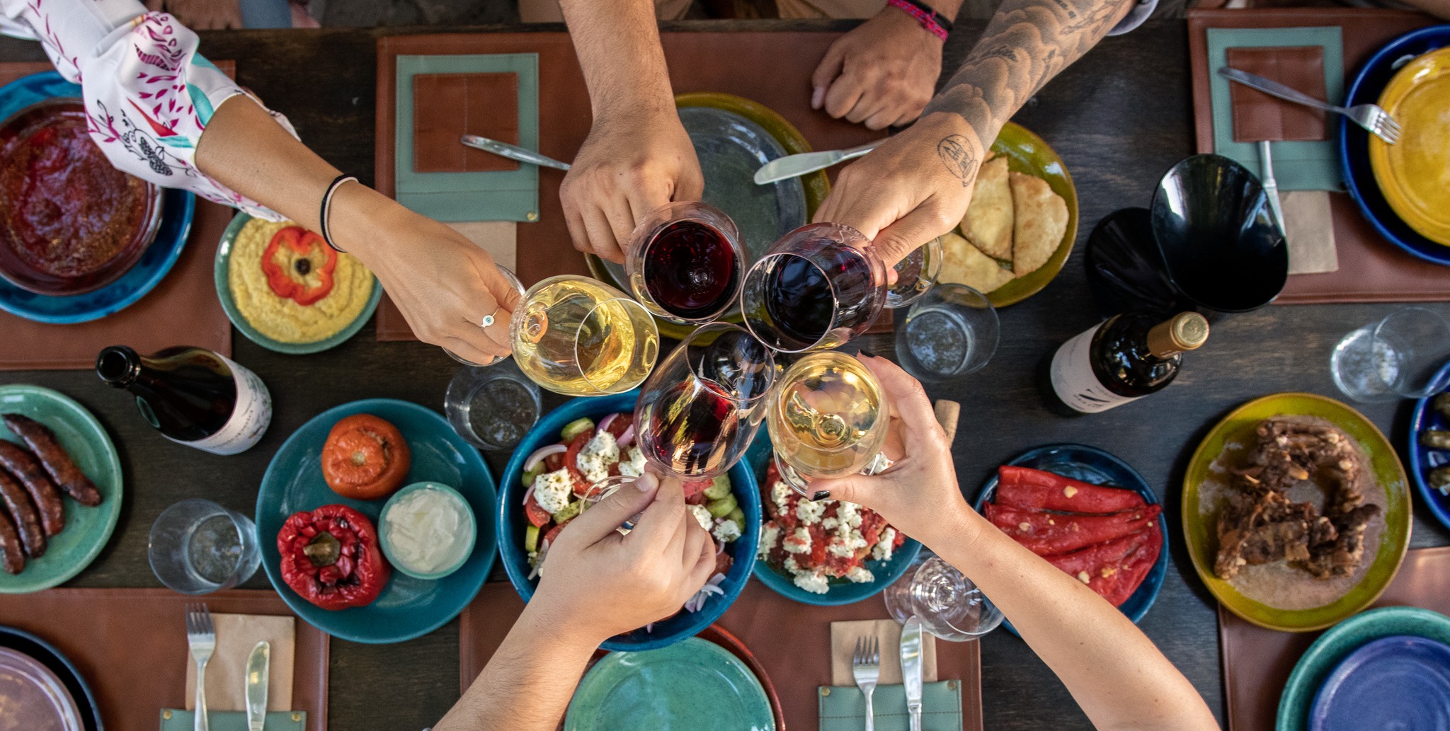 Friends raising glasses of wine over a table of colourful local dishes
