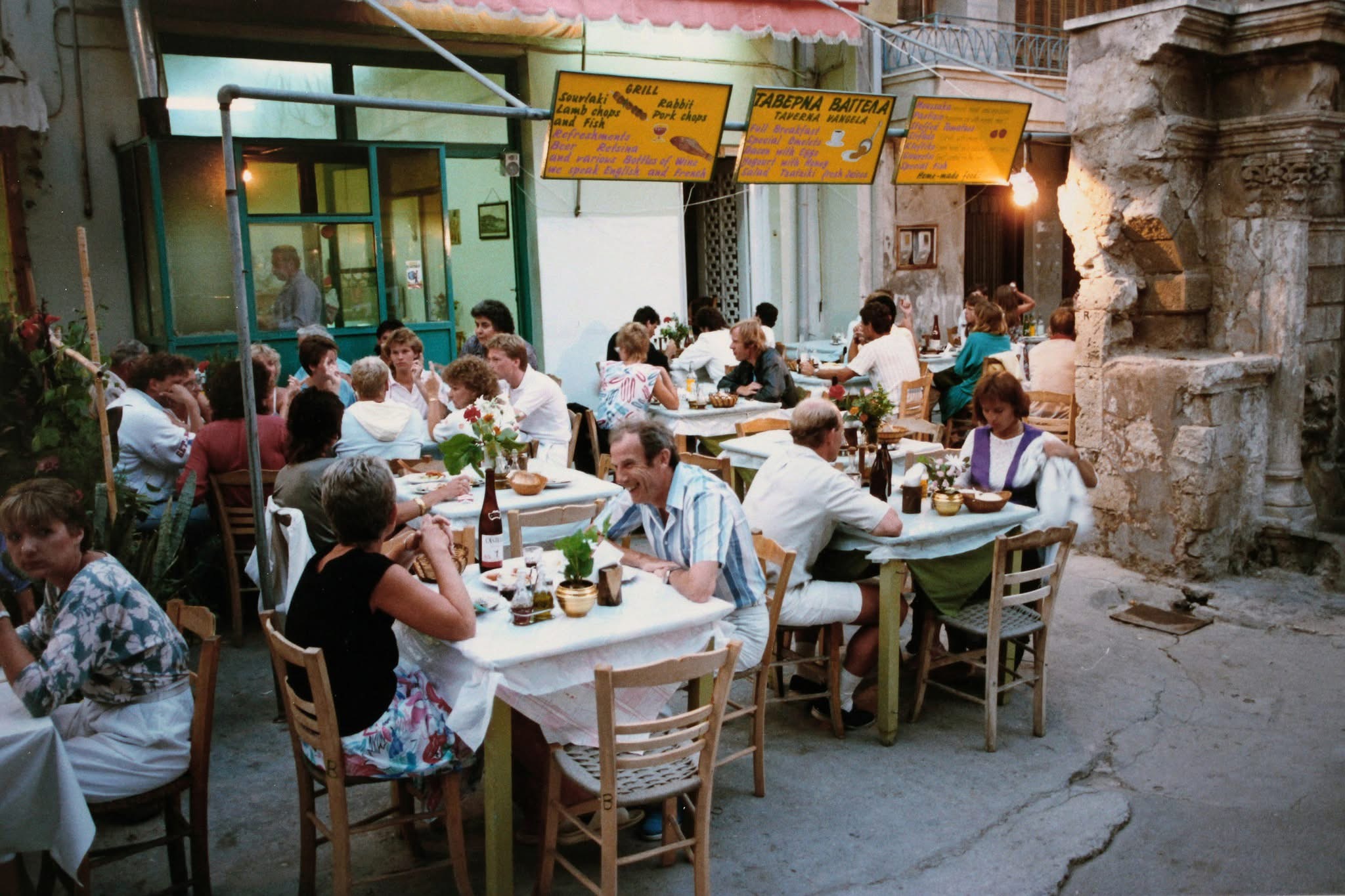 People sharing a meal at tables in a Cretan street