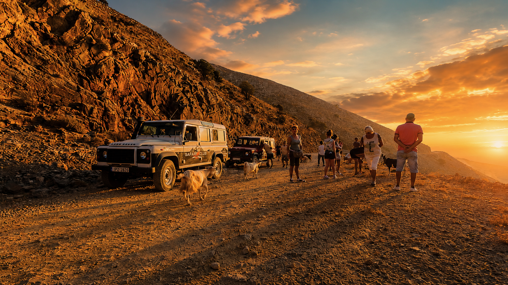 Four-wheel-drive vehicles and travellers on a mountain track at sunset