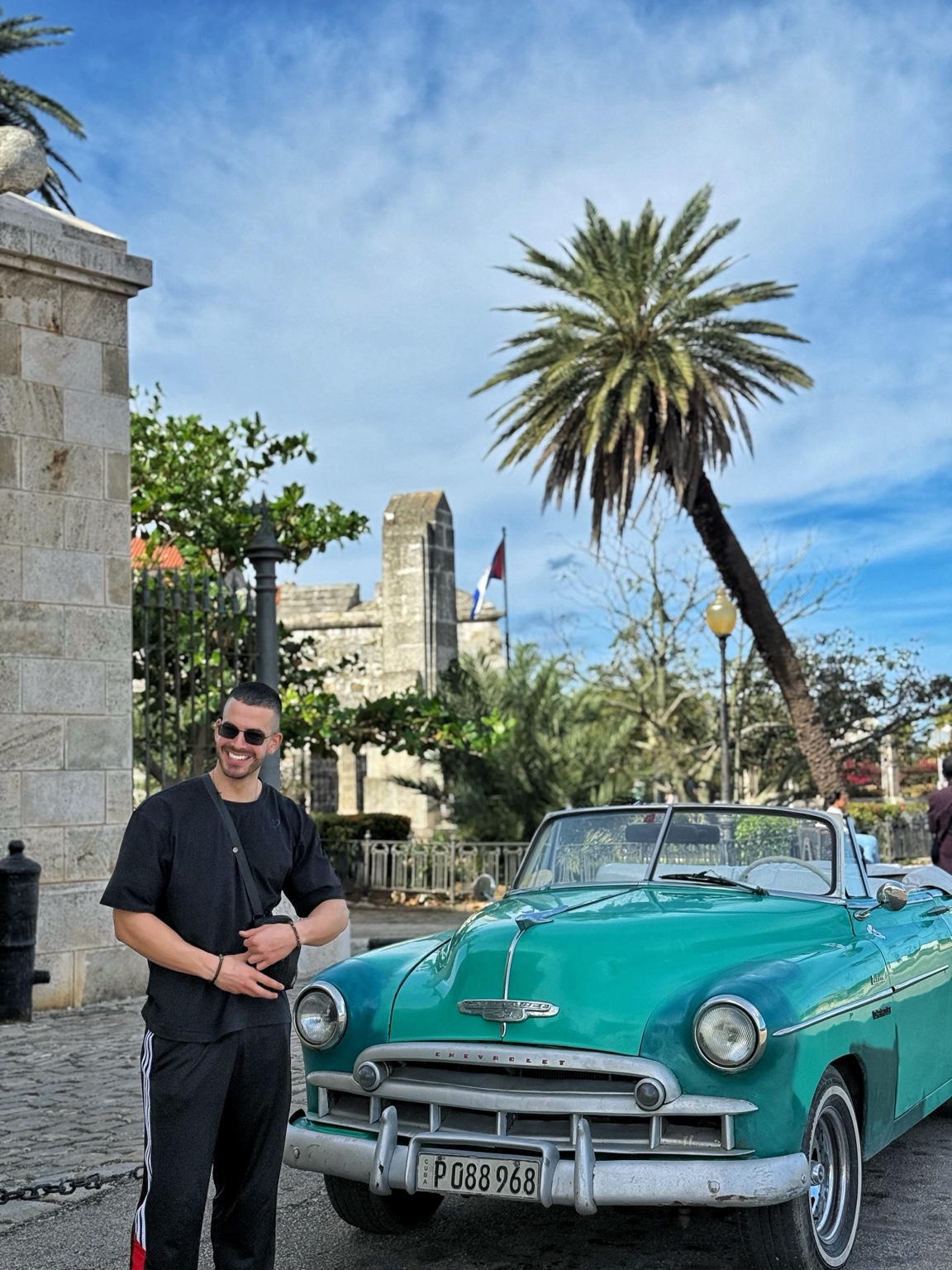 Fotis beside a turquoise vintage car while travelling