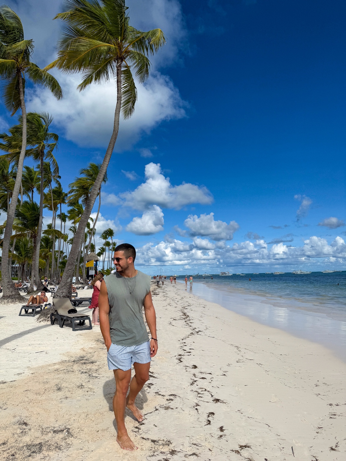 Fotis walking beside the sea on a palm-lined beach
